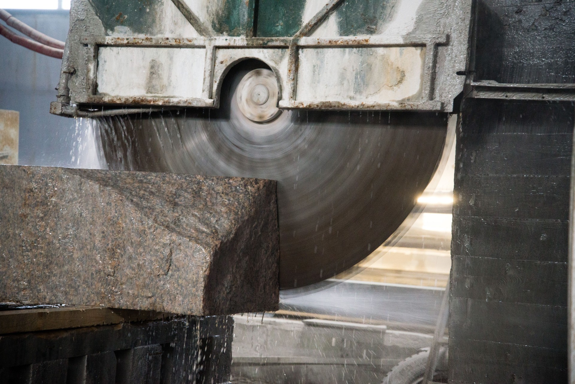 Granite processing in manufacturing. Cutting granite slab with a circular saw. Use of water for cooling. Industrial sawing of granite
